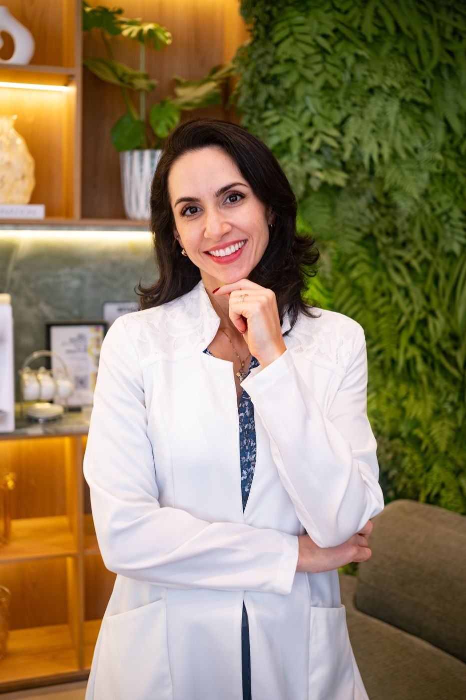 Dra. Svenja de jaleco branco com a mão no queixo, sorrindo