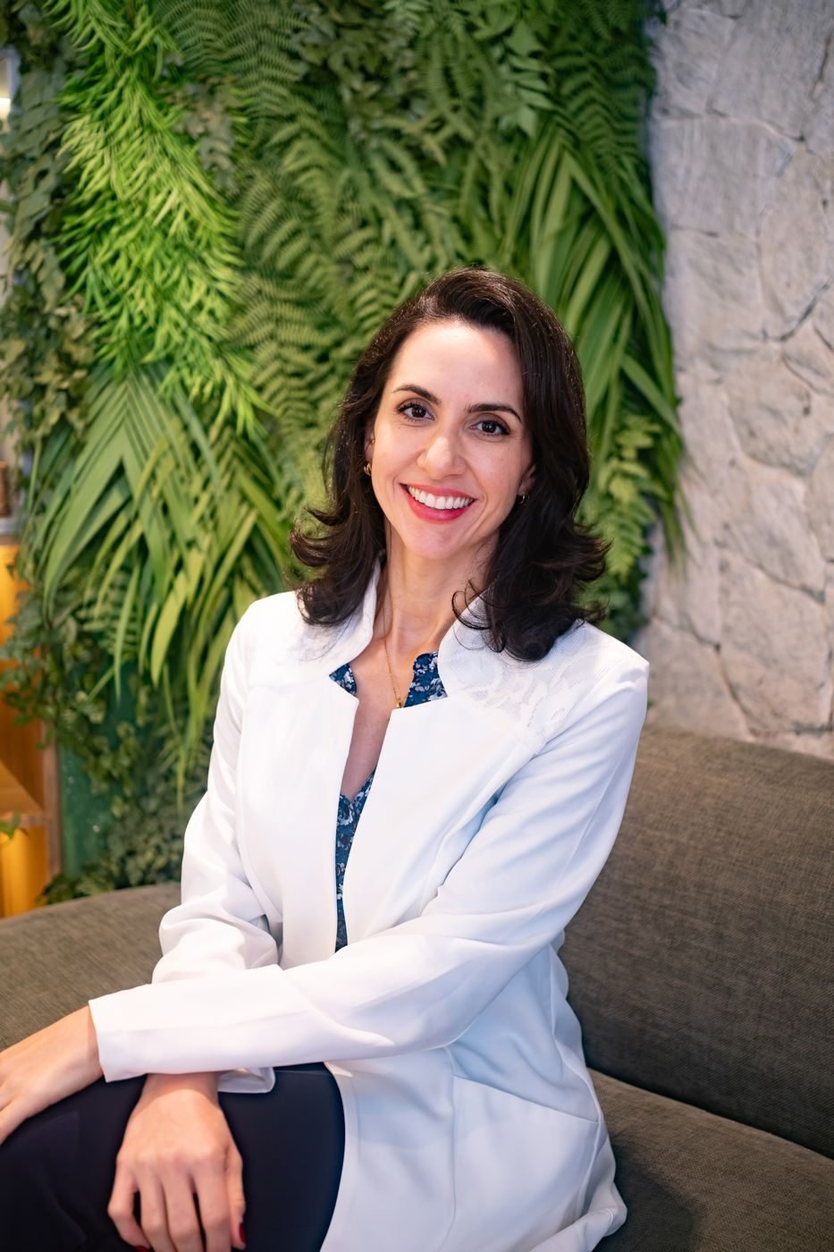 Dra. Svenja Lopez de jaleco branco, sorrindo no consultório
